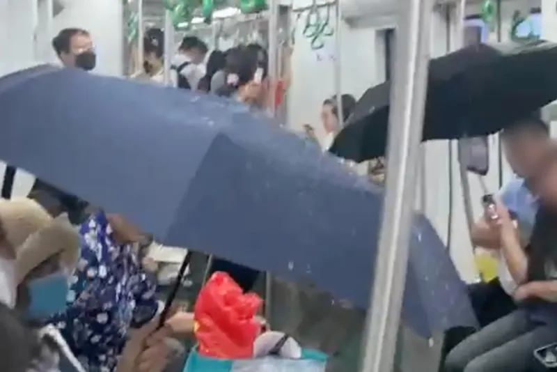 Nhiều hành khách phải che ô và di chuyển khỏi khu vực có nước chảy. Ảnh cắt từ clip Trên một đoàn tàu đường sắt trên cao tuyến Cát Linh - Hà Đông (Metro Cát Linh - Hà Đông) bị dột nước khiến nhiều hành khách phải che ô và di chuyển khỏi khu vực có nước chảy. Ảnh cắt từ clip