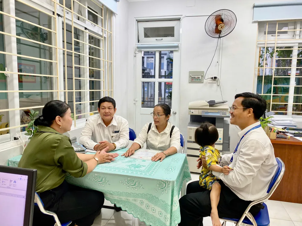 Ông Nguyễn Văn Thành (Phó chủ tịch UBND phường 8, quận 10) (bế bé V) và ông Huỳnh Tấn Đạt (Giám đốc Trung tâm Trợ giúp pháp lý Nhà nước TP.HCM) cùng chị Phượng đang làm việc với nhà trường để làm thủ tục nhập học cho bé V. Ảnh: YC can-cuoc-cong-dan-2.jpg