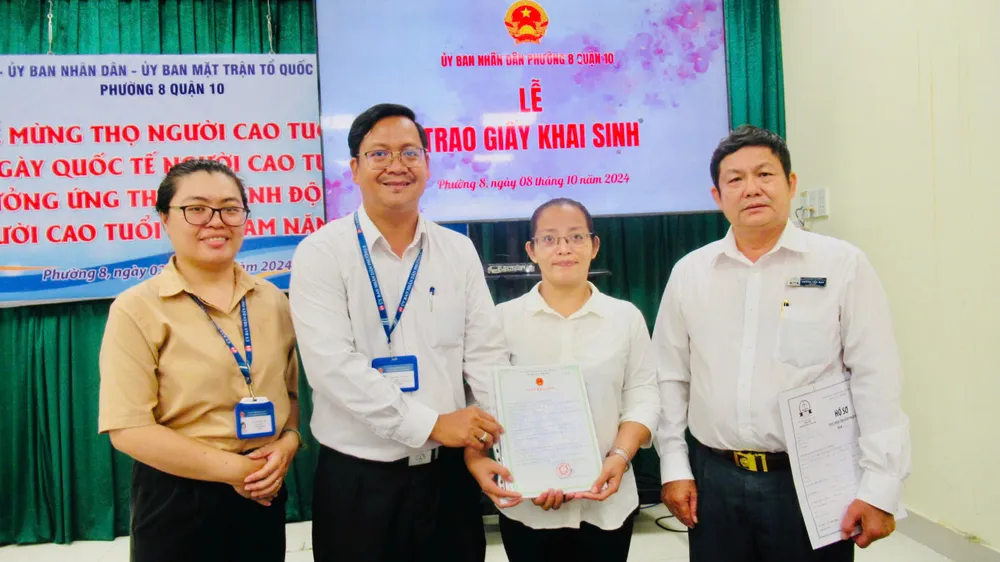 Ông Nguyễn Văn Thành, Phó chủ tịch UBND phường 8, quận 10 (thứ hai từ trái qua) trao giấy khai sinh cho chị Phượng. Ảnh: YC can-cuoc-cong-dan.jpg